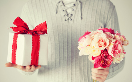 プレゼントと花束を両手にもつ男性